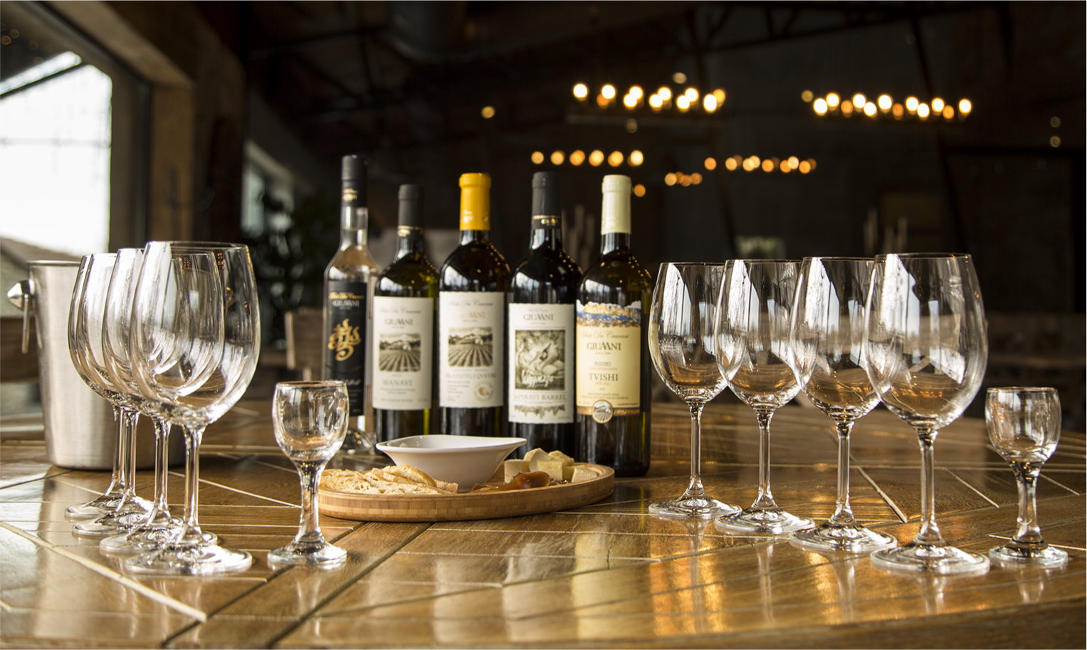 Selection of Giuaani wines with glasses and cheese platter on a wooden table