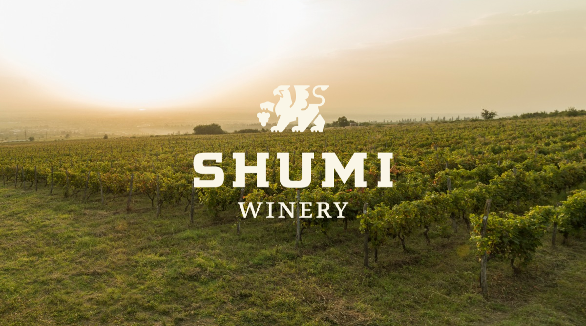 Shumi winery logo against the backdrop of vast and rich vineyards