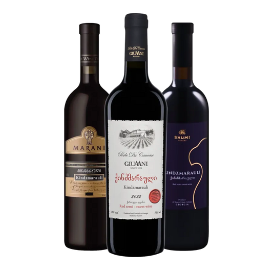 Three bottles of Kindzmarauli wine, each with a distinct label and color scheme, representing the Marani, Giuaaniki, and Shumi brands.